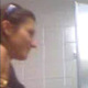 A hidden camera mounted behind a public restroom toilet records a woman peeing.